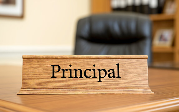 Principal office desk with nameplate. Black executive chair, wooden shelves, and files behind. Ready for school administration leadership meetings or educational policy discussions.