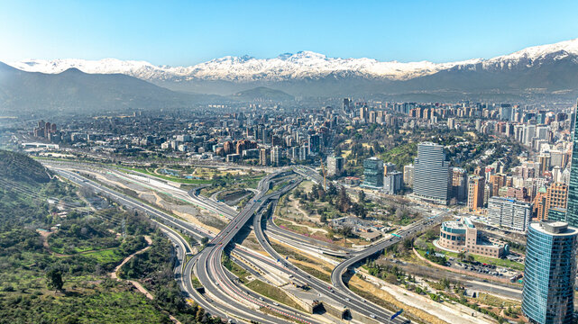 Aerial view of the highway interchange, modern skyscrapers, and snow-capped Andes mountains in the background of Santiago, Santiago Metropolitan, Chile.