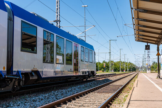 Modern Regional Passenger Train at Railway Station Platform with Electrified Tracks on a Sunny Day