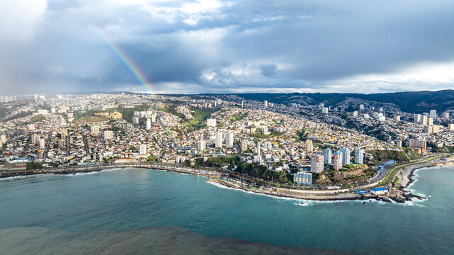 Aerial view of Vina del Mar coastline featuring dense urban development, high-rise buildings, and a rainbow over the city in Vina del Mar, Valparaiso, Chile.