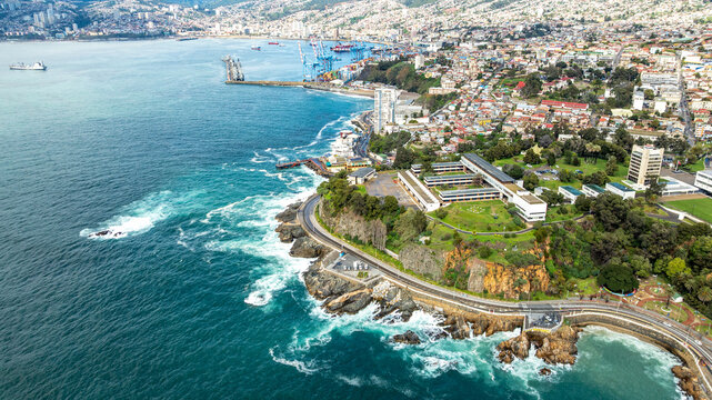 Aerial view of the coastal landscape featuring rocky shorelines, modern buildings, lush green parks, and the Pacific Ocean in Vina del Mar, Valparaiso, Chile.