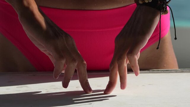 Beach relaxation hands dancing rhythmically on white table by ocean. Static close-up shot captures sunlight hitting skin during a tranquil summer holiday.