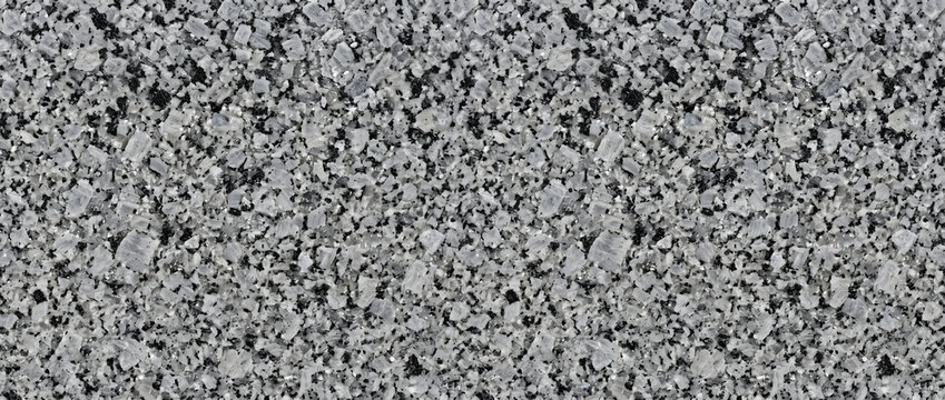 Granite texture with a detailed speckled pattern of grey and black minerals provides a sophisticated natural stone background for modern architectural surfaces