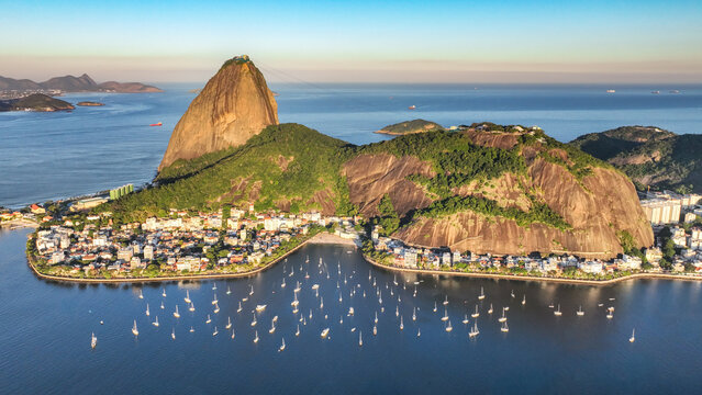 Aerial view of Sugarloaf Mountain and Urca with sailboats anchored in the bay, surrounded by lush hills and urban buildings in Rio de Janeiro, Rio de Janeiro, Brazil.
