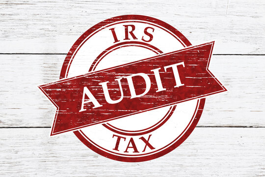 Red distressed IRS Tax Audit stamp on weathered wood for financial review