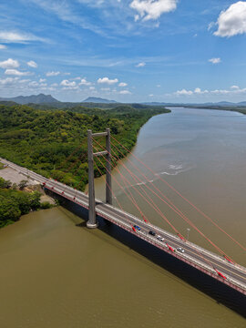 Aerial view of Puente La Amistad spanning the Tempisque River, surrounded by lush tropical forest under a blue sky in Bagaces, Guanacaste Province, Costa Rica.