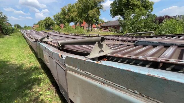 Detailed perspective along the upper deck of a flat freight rail wagon in Germany. Focus on the steel loading platform, industrial construction and modern railway transportation infrastructure.