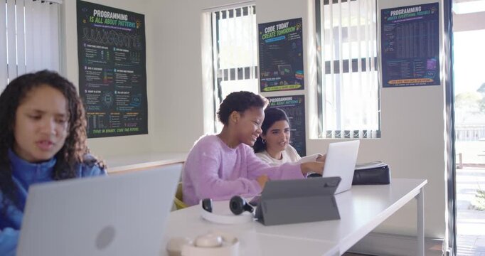 Diverse teens working at code lab, camera shifting causing right pair moving closer, typing laptop