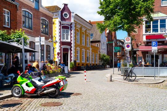 Historic street scene in Husum's old town with restaurants, caf&eacute;s, cobblestone streets and colorful buildings on a sunny summer day.