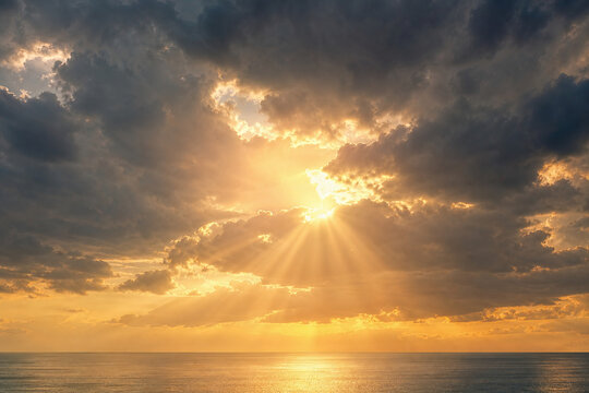Golden sun rays through storm clouds at horizon