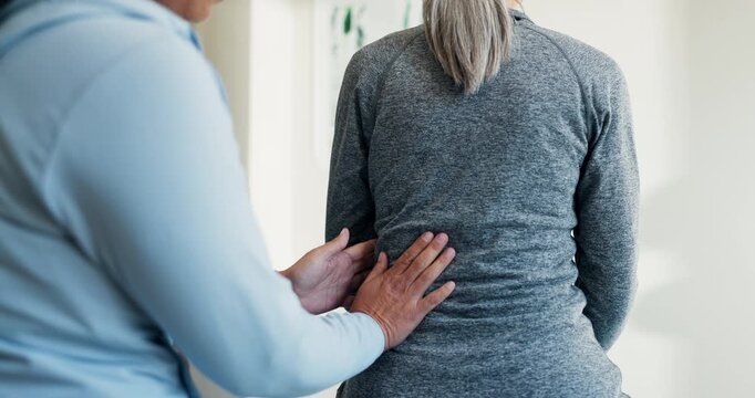 Back pain, massage and women in physical therapy clinic for healing, consultation or healthcare. Person, senior patient and spine injury with rehabilitation session, chiropractic and joint wellness