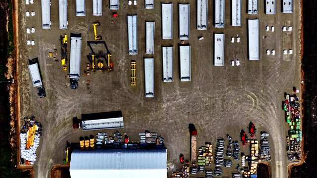 Riga, Latvia - 03 August 2025: Aerial view of a construction storage site featuring rows of concrete segments, trucks, and industrial equipment on a gravel yard.
