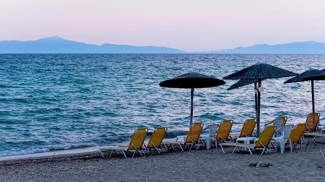 Greek beach yellow chairs and thatched umbrellas along the shore
