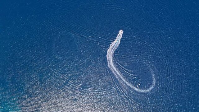 Boat leaves a curved wake across the deep blue sea near Greece