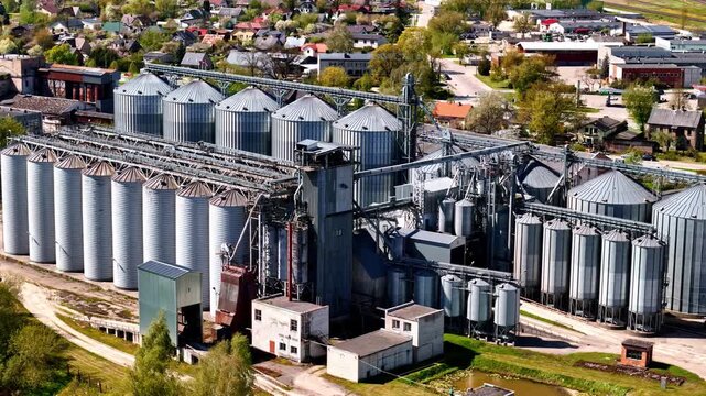 Riga, Latvia - 05 May 2025: Aerial view of a large grain elevator facility with numerous metal silos and industrial structures surrounded by rural landscape.