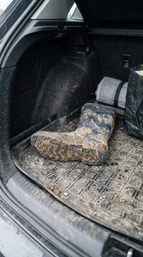 A solitary muddy rubber boot resting in a car trunk after an adventurous exploration through rural terrain