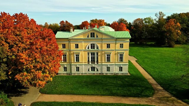 Riga, Latvia - 06 November 2024: Aerial view of Mezotne Palace with its yellow facade and green roof surrounded by autumn trees in a park.