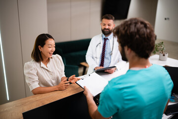 Patient completing paperwork at medical reception desk