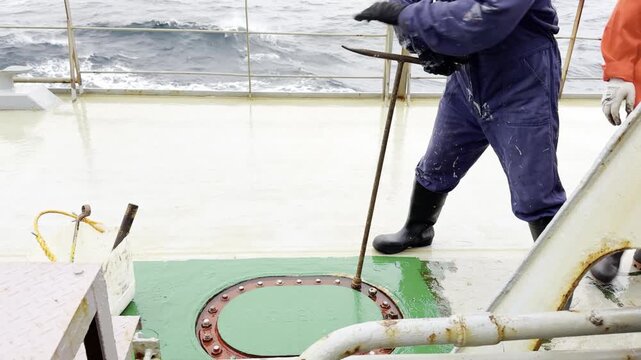 unscrewing manhole of ballast tank cover on board the ship