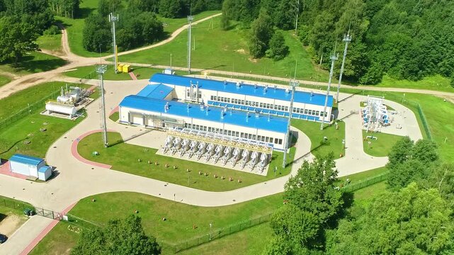 Latvia - 09 October 2023: Aerial view of a gas compressor station surrounded by lush green forests and infrastructure.