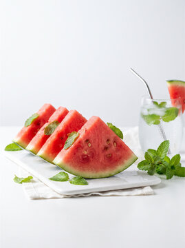Fresh watermelon slices on a white tray. Summer fruit snack with mint and cold water.