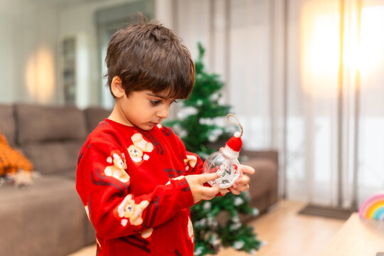 Young boy decorating christmas tree with ornament