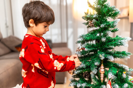 Little boy decorating christmas tree with ornaments
