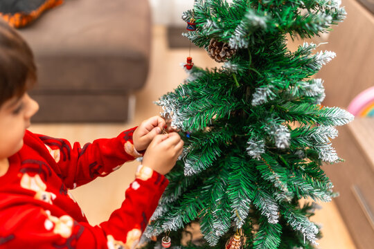 Young boy decorating christmas tree for holiday celebration