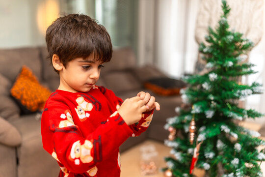 Young boy decorating christmas tree with mother at home