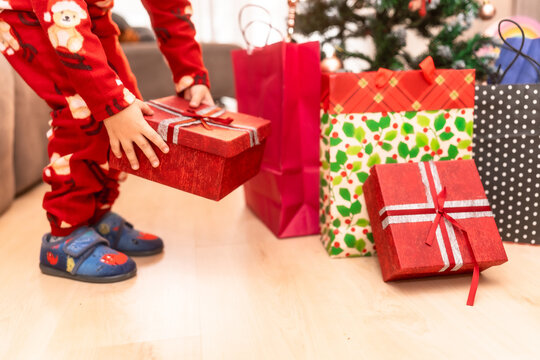 Child holding christmas gift box wearing pajamas