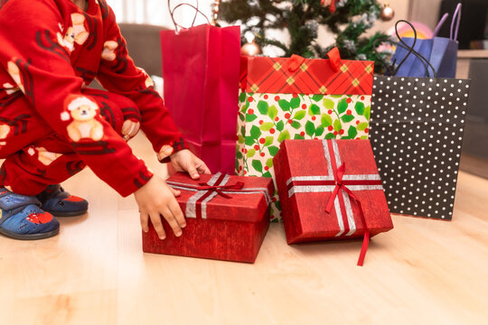 Child wearing pajamas reaching for christmas present