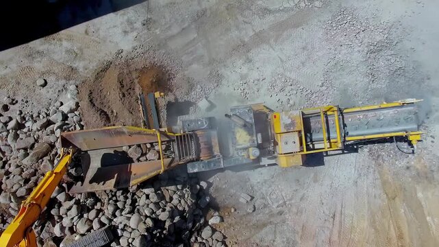 Latvia - 19 February 2023: Aerial view of an industrial rock crusher machine processing stones at a construction site.
