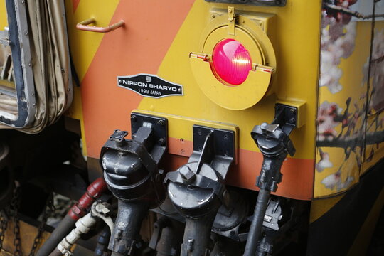 A red tail light glows on a diesel train.