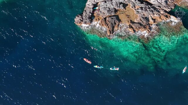 Aerial view of colorful kayaks near rocky Adriatic coastline with crystal clear turquoise water in Pula Croatia