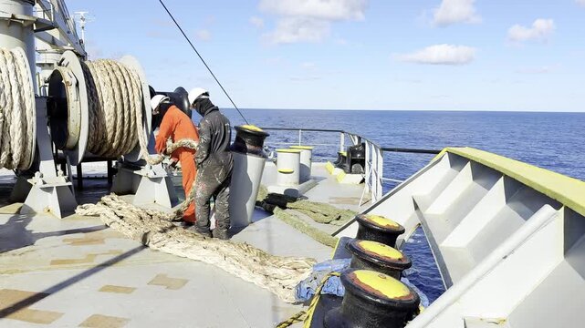 Workers on site. Maritime crew uncoiling mooring ropes from winch machinery.