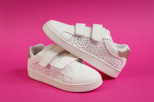 Pair of White Children's Sneakers on Pink Background. Stylish Kids Fashion Footwear