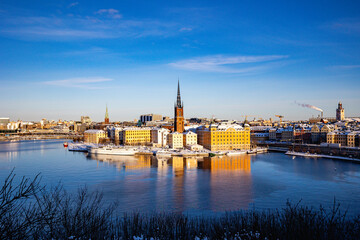 Obraz premium Panoramic view of Riddarholmen island and church spire in winter with snow and reflections in Stockholm, Sweden.