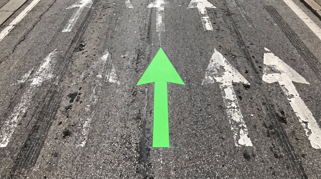 Right Direction Concept, Bright Green Arrow Painted Among Faded Old Road Arrows