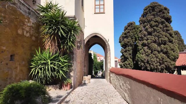Camminando verso un arco in pietra lungo un sentiero acciottolato a Rodi, in Grecia.