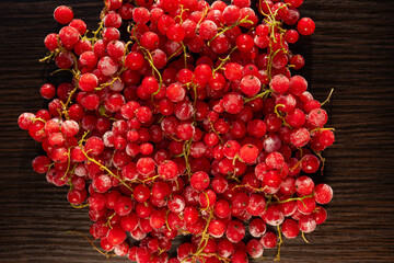 Top view of frozen red currants with frost on dark wooden background © Ellen