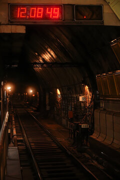 Dimly lit subway tunnel featuring a red digital clock. Concept emphasizes urban infrastructure, transportation, and time management, suitable for commercial use in related sectors.