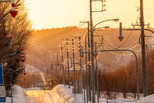 Winter evening landscape in Hokkaido with power lines glowing in golden sunset light