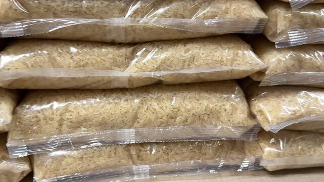 Neatly stacked rice packages create a well organized grocery display, offering shoppers a wide selection of staple food products for home cooking and commercial supply. Close up.