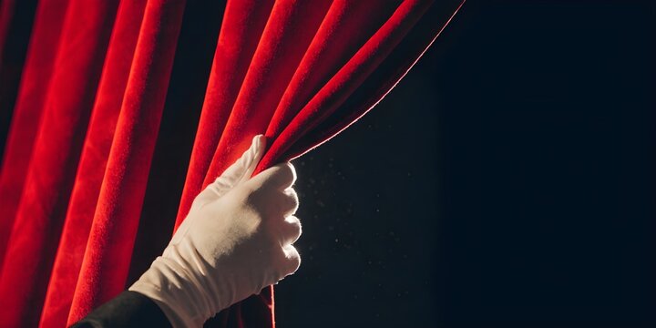 Hand in white glove pulls back red velvet curtain revealing darkness