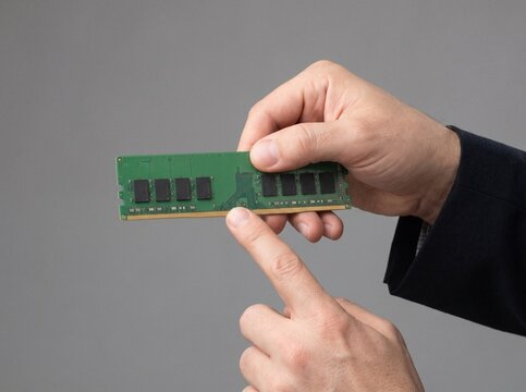 Close-up of a person in a suit pointing to a computer RAM memory module