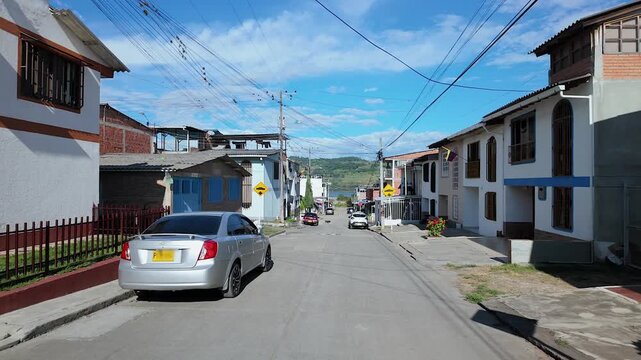 scenic street view of a small town in colombia with colorful houses and parked cars under a blue sky