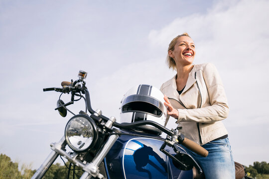 Happy female biker on motorcycle looking away