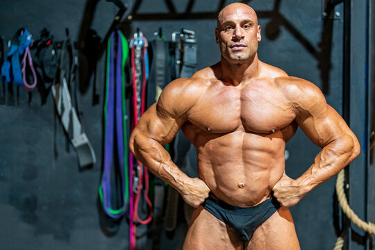Confident bodybuilder with arms akimbo flexing muscles in gym