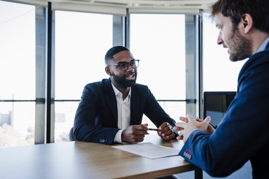 Smiling client talking to businessman in office