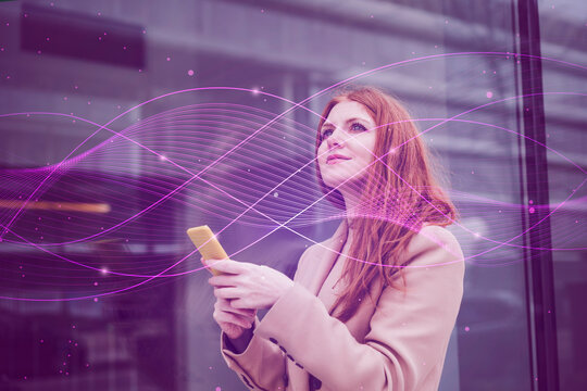 Thoughtful businesswoman with smart phone in front of building